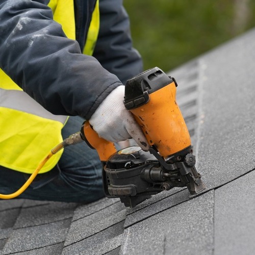 roofer nailing down gray shingles