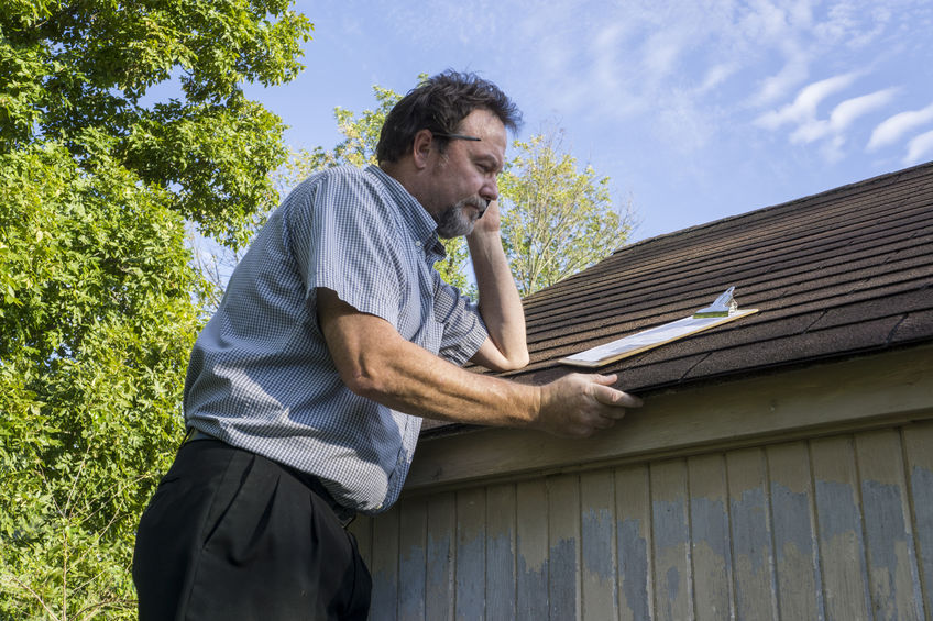 Insurance adjuster checking a roof for damage.